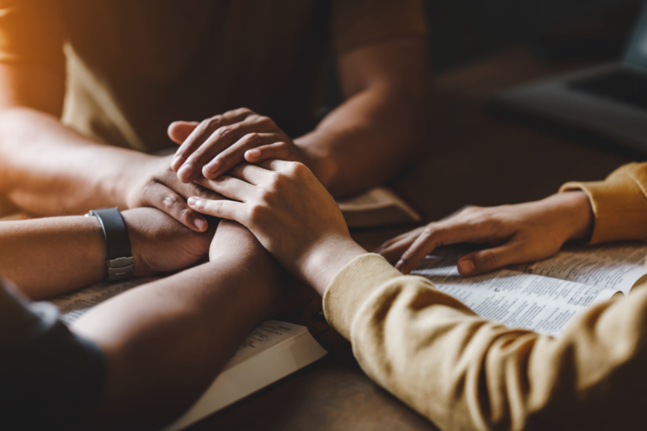 Hands holding each other in support as a group of people