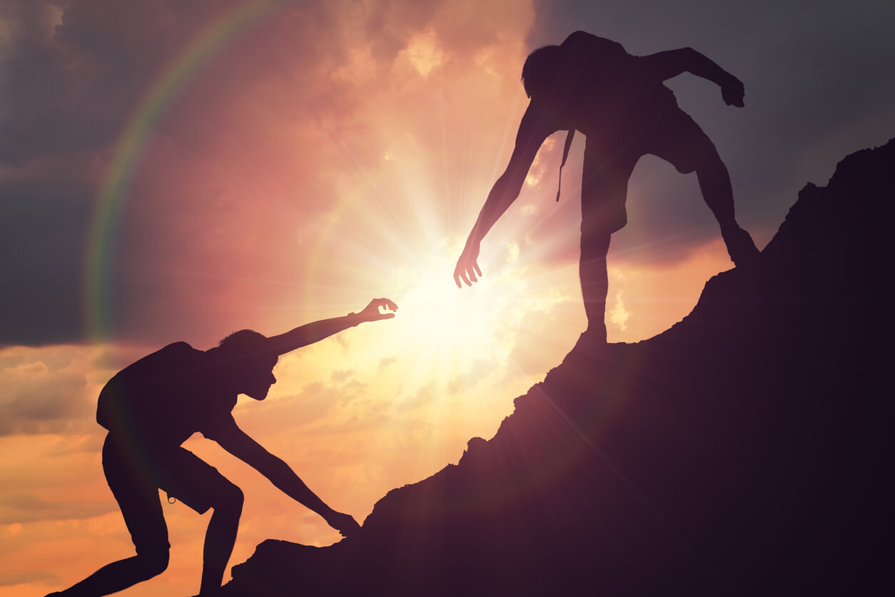 People climbing mountains against the background of the setting sun