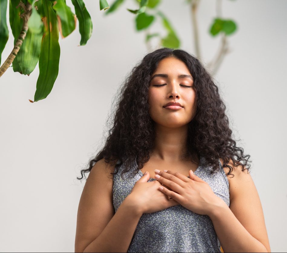 Beautiful multiracial woman doing breathing exercise at home