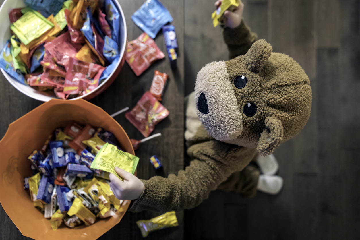 Cute baby boy inside bear costume eating or grabbing candies