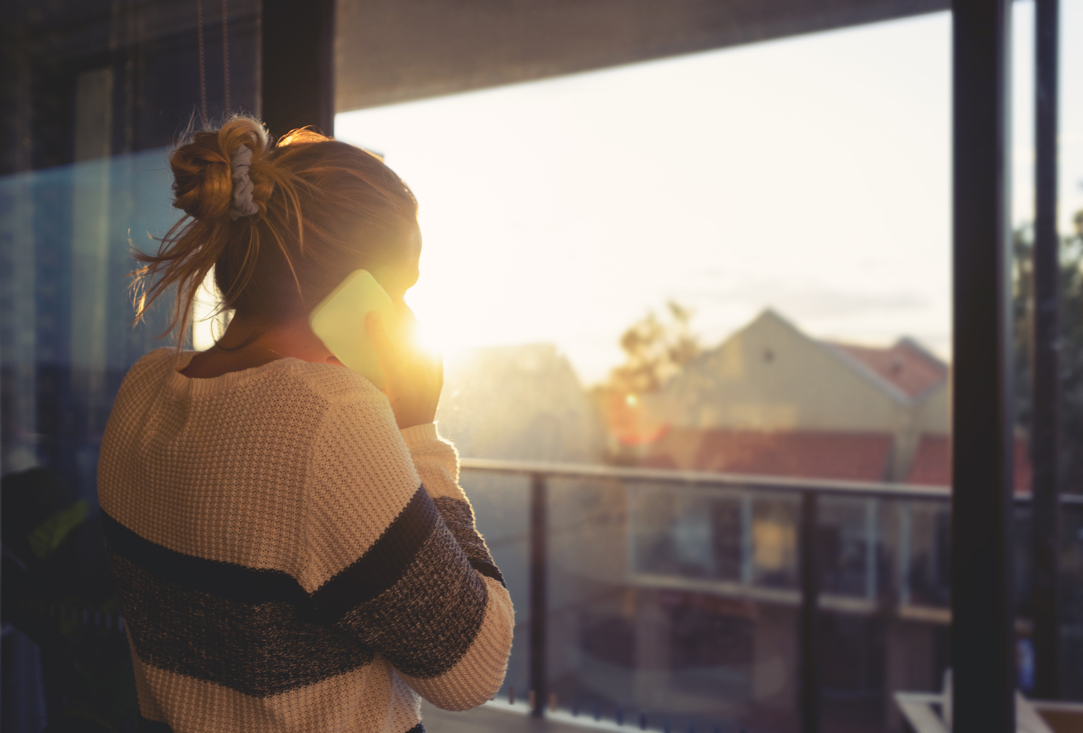 Woman looking through the window at sunset