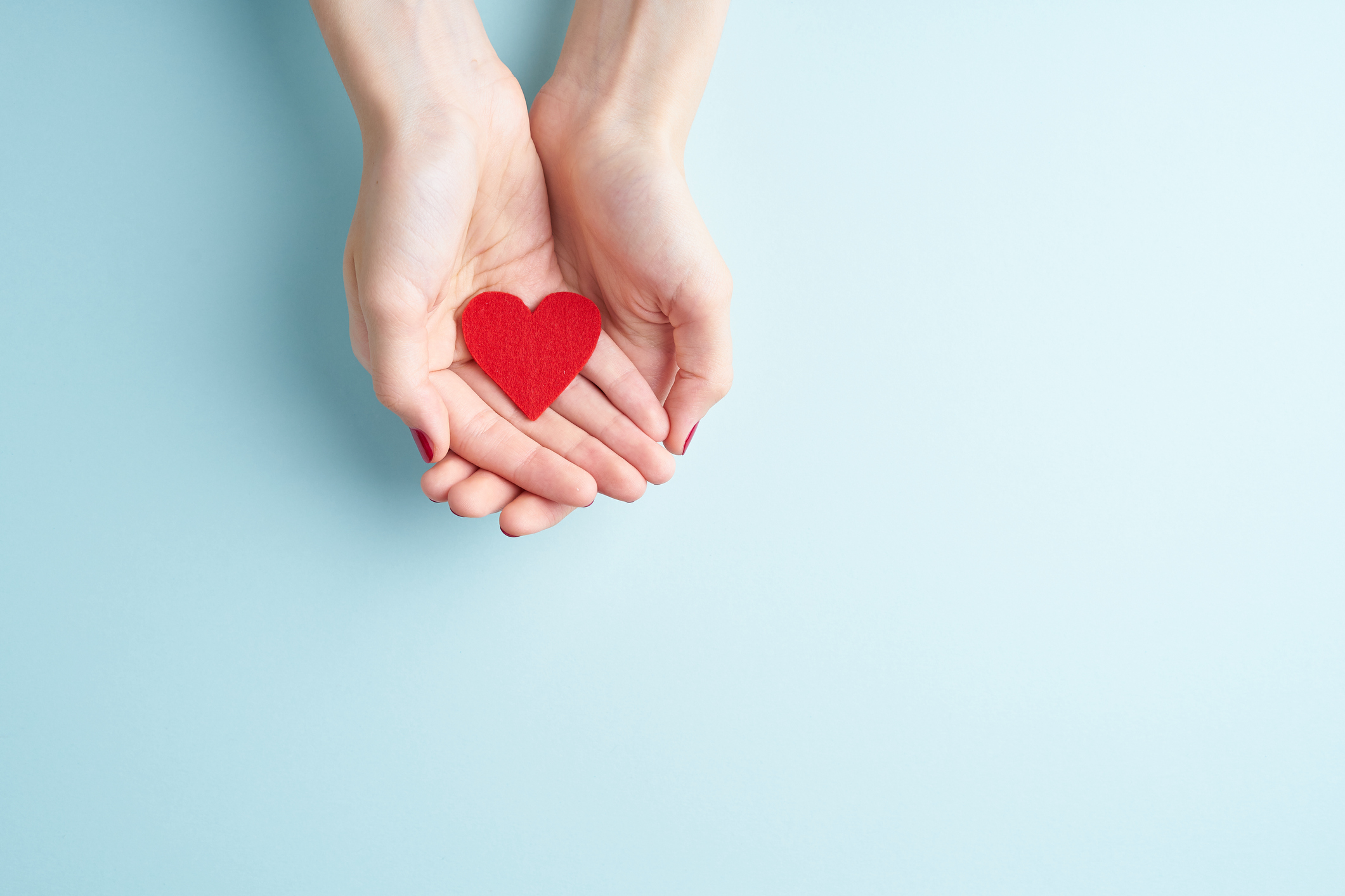 Young hands holding or giving a red heart