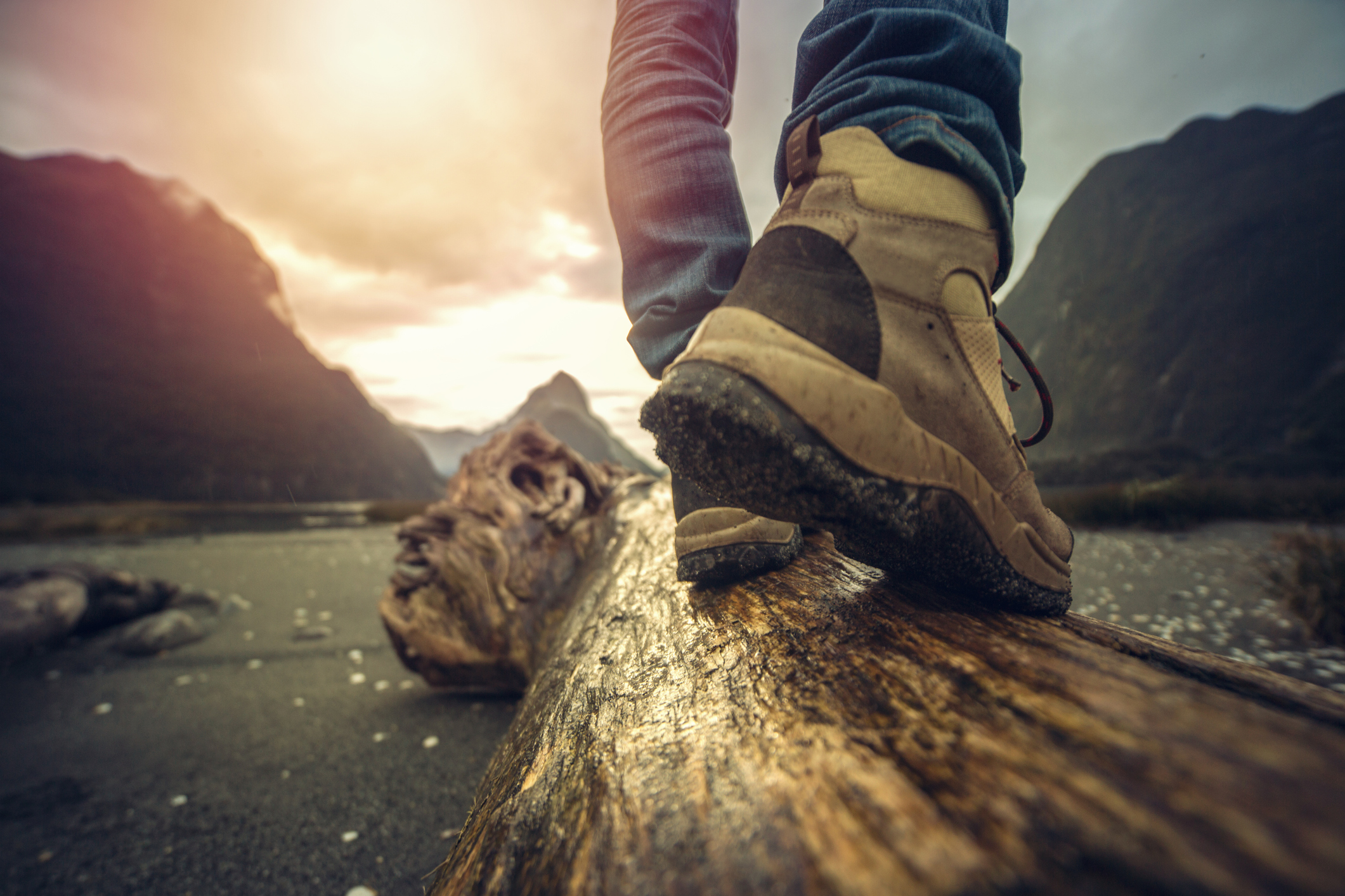 Low angle view of hiker standing on log in mountain scenery