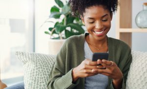 Cropped shot of an attractive young woman using her cellphone while sitting in the living room during the day