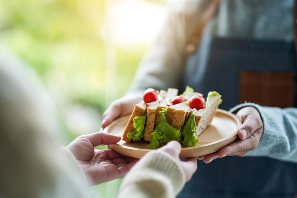 A waitress holding and serving whole wheat sandwich