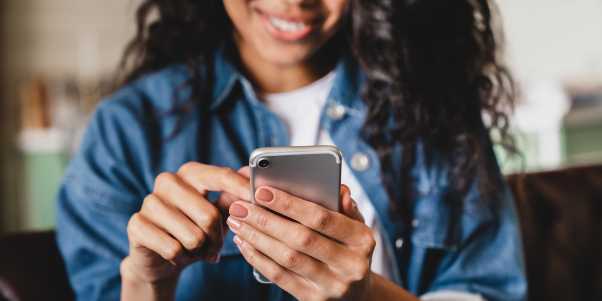 A young woman smiling as she scrolls through her phone